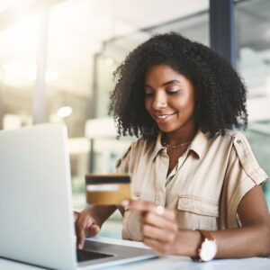 woman looking at credit card behind laptop