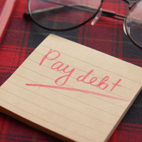 A sticky note with the words "pay debt"